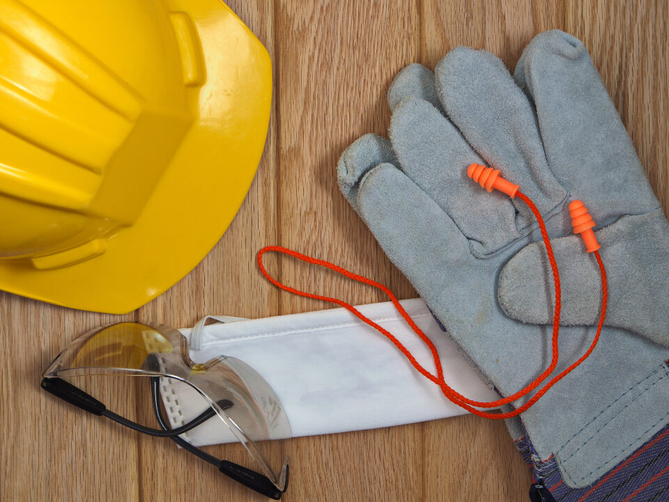 Casque de chantier, gants et plans posés sur un établi